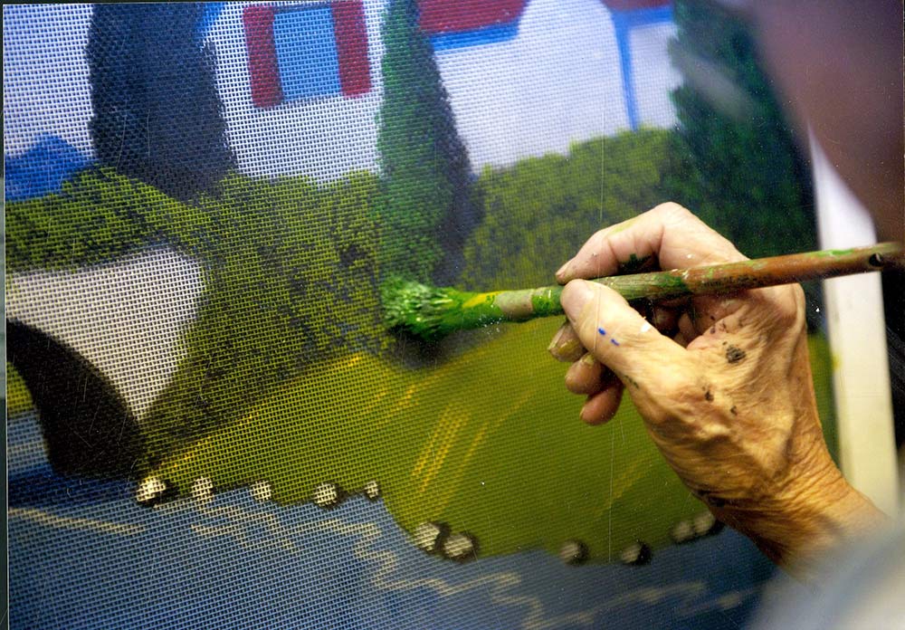 A handing holding a bush, painting on a window screen