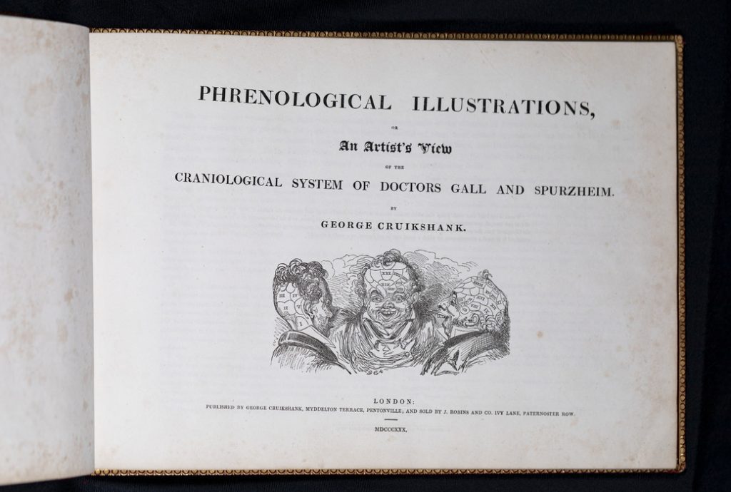 The title page of George Cruikshank's "Phrenological Illustrations, Or An Artist's View of the Craniological System of Doctors Gall and Spurzheim." There are three men with exaggerated smiles and abnormal head shapes. Each man has different sections drawn onto their heads.