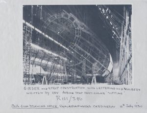 A monochromatic photograph tinted blue. Text below the image reads "GIRDER AND STRUCT CONSTRUCTION, WITH LETTERING AND NUMBERS WRITTEN BY O.G.V. DURING THAT PARTICULAR "SITTING." R101/396. PHOTO FROM DRAWING OFFICE, ROYAL AIRSHIP WORKS. CARDINGTON 16TH July 1930."