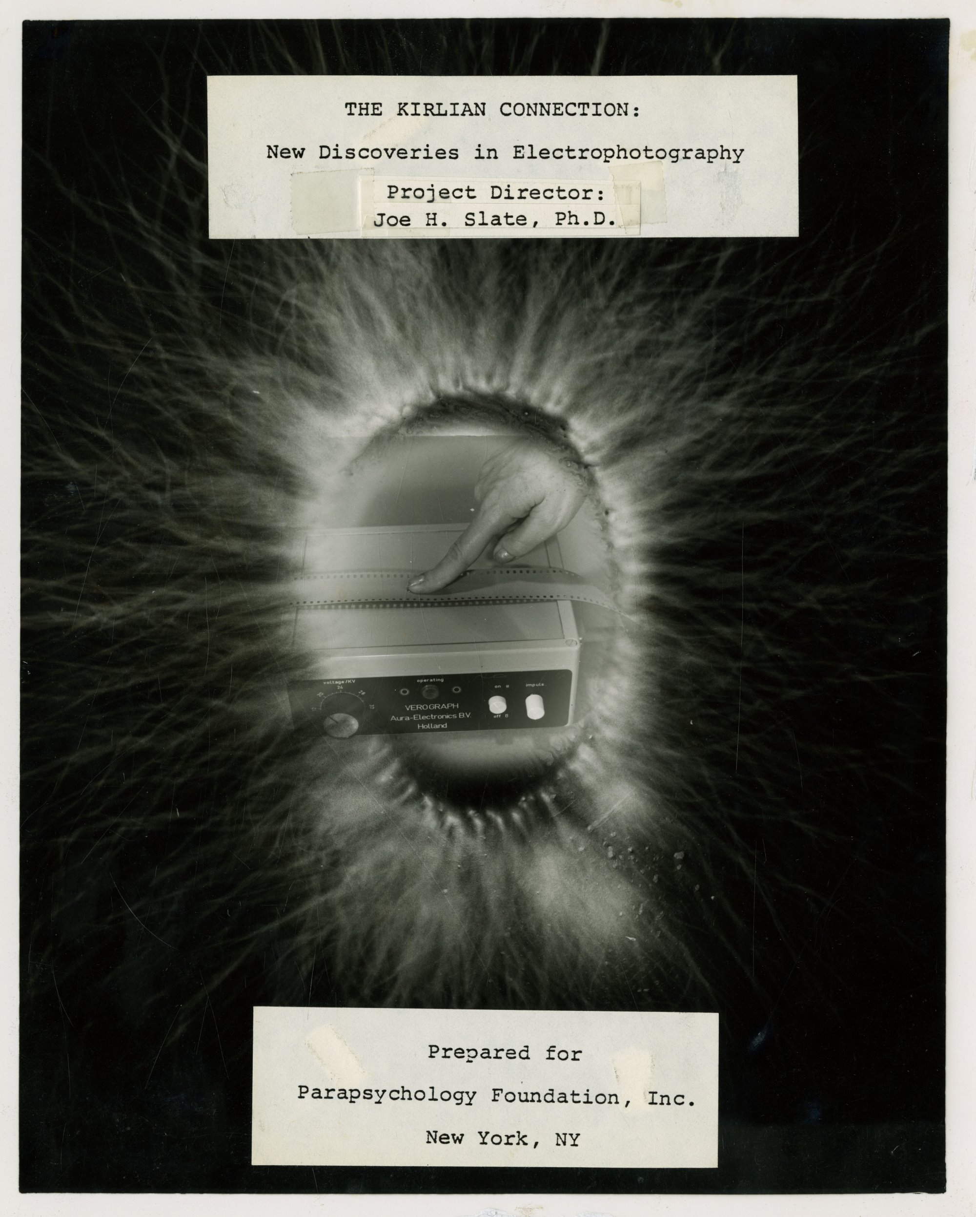 An ovaloid Kirlian projection with a finger touching a rectangular device superimposed inside of the projection. The title and author information are on papers laying on above and below the image, typed in a monospaced font. 