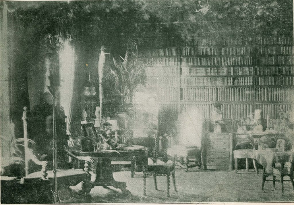 Print of the lantern slide photograph with a green tint showing an ornate library room with a mysterious light in the center. The apparition appears more prominently in this version of the image.