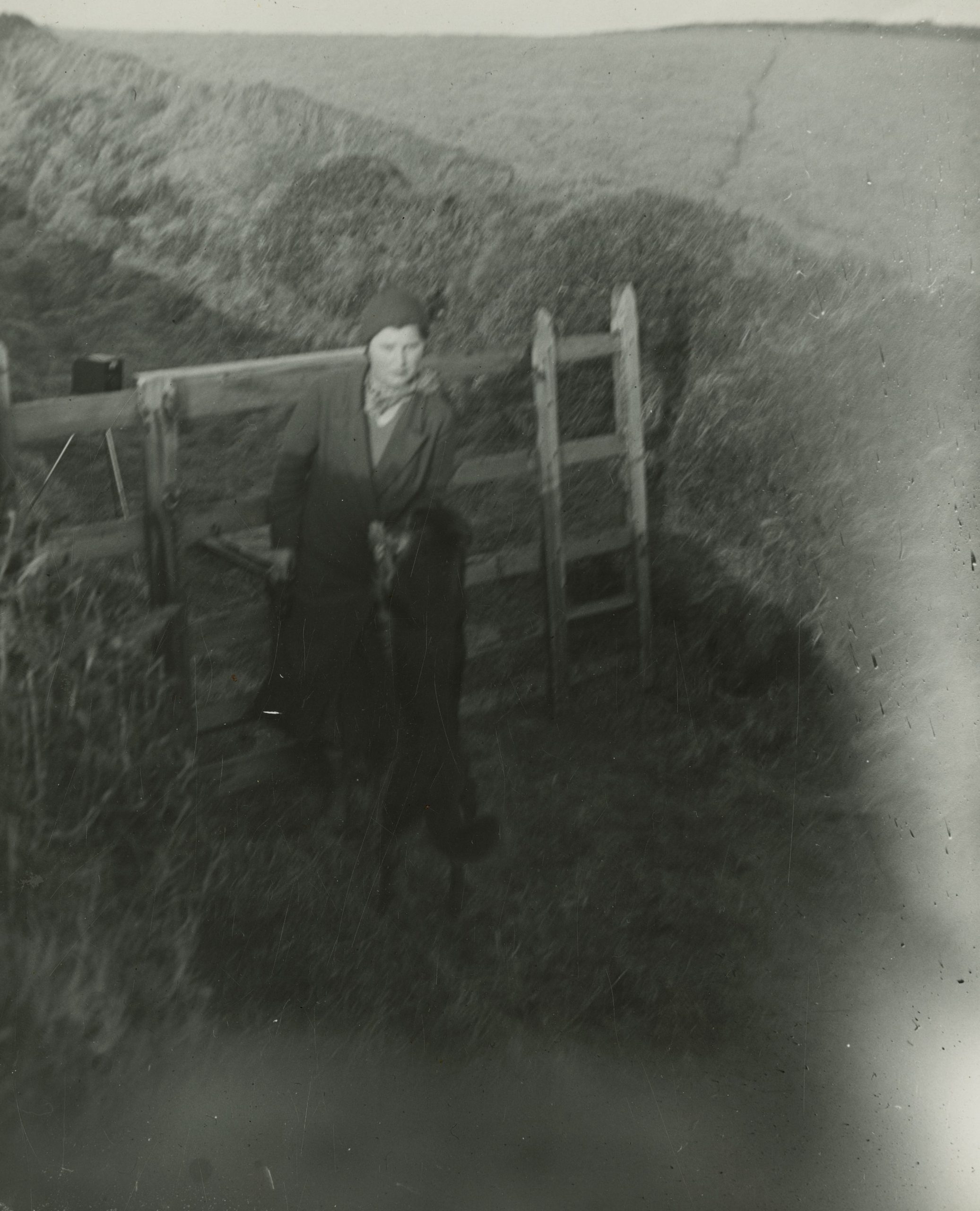 A photograph of Voirrey Irving and dog Mona, in front of the fence where Voirrey photographed Gef. Mona is excitedly jumping on Voirrey.