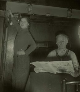 The photograph shows Voirrey Irving pointing to a hole in the ceiling. Her father Jim Irving is shown reading a newspaper. Gef was said to read from Mr. Irving's paper from this location.