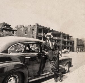 man leaning against car in front of apartment complex