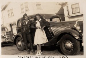 Two women leaning against black car