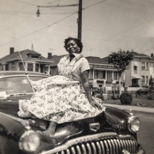 woman in dress sitting on the hood of car