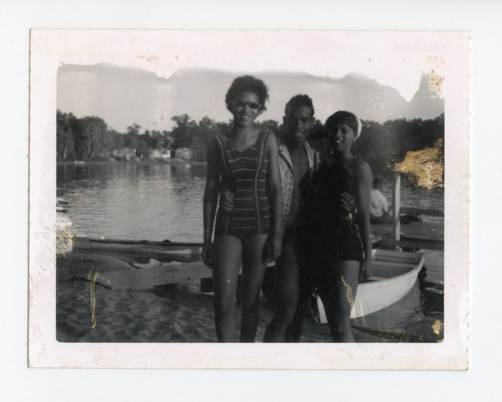 Three people posing along a lake shore.