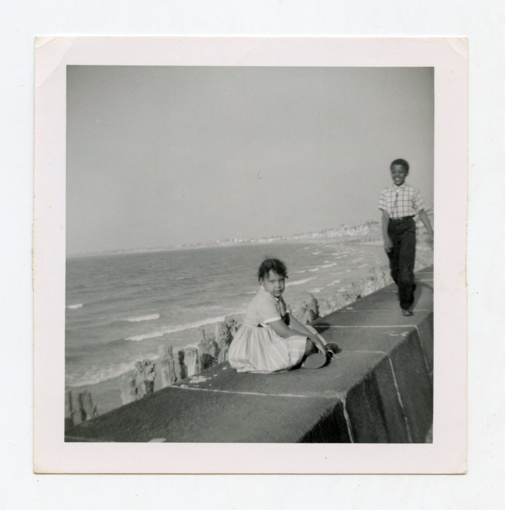 Two kids standing on beach barrier.