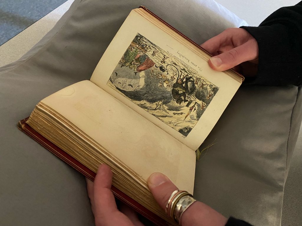 Picture of Sarah in the reading room holding open Letters on Demonology and Witchcraft